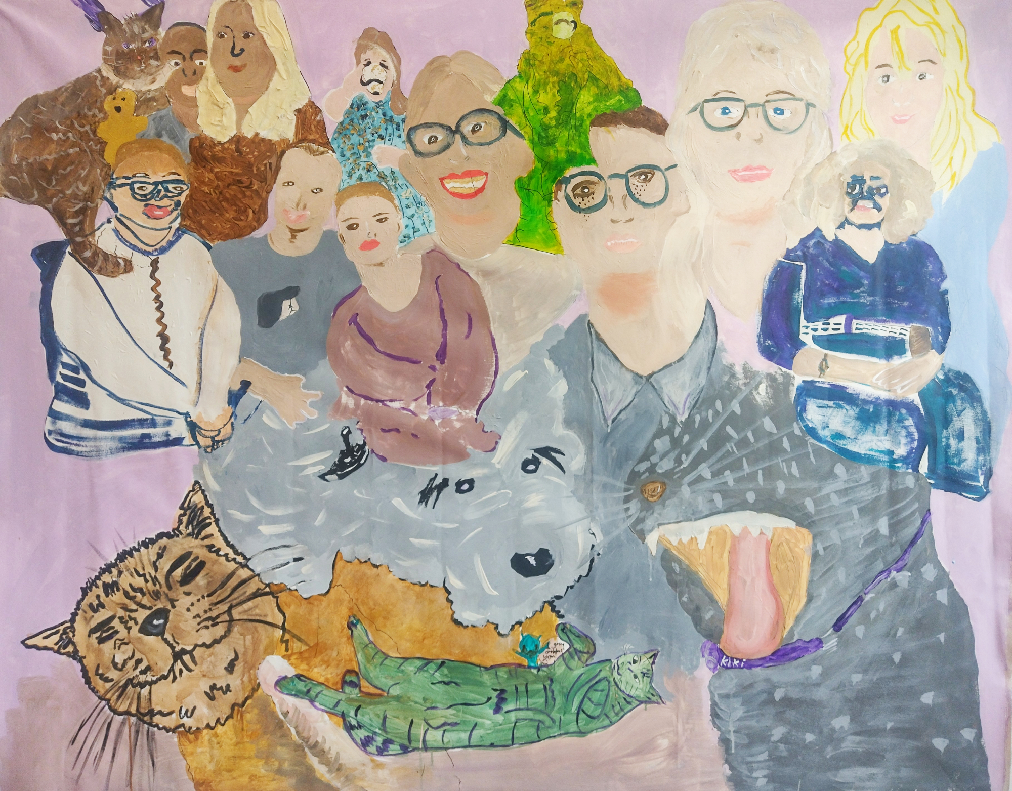 Expressive group portrait featuring people of different ages alongside animals, painted in a playful, illustrative style. A large grey dog with its tongue out dominates the foreground, accompanied by a ginger cat, a fluffy grey dog, a brown cat and a green frog. Behind them, a group of smiling people fills the composition against a soft pink and lavender background.
