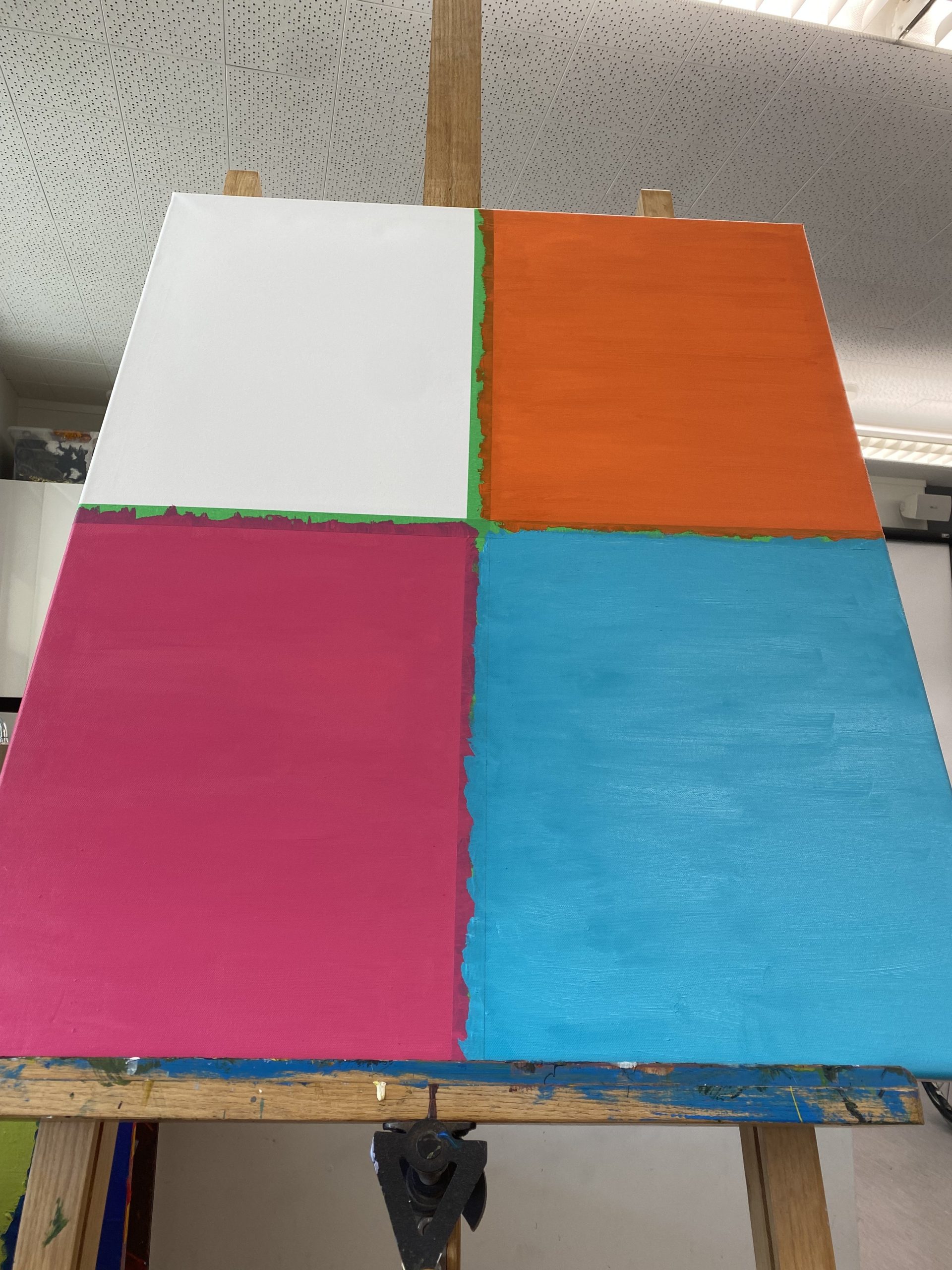A large canvas divided into 4 oblong sections divided by a thick green line. 3 of the sections now painted. Top right is the orange, bottom left a rich fuschia pink and to the right of this, a deep baby blue.