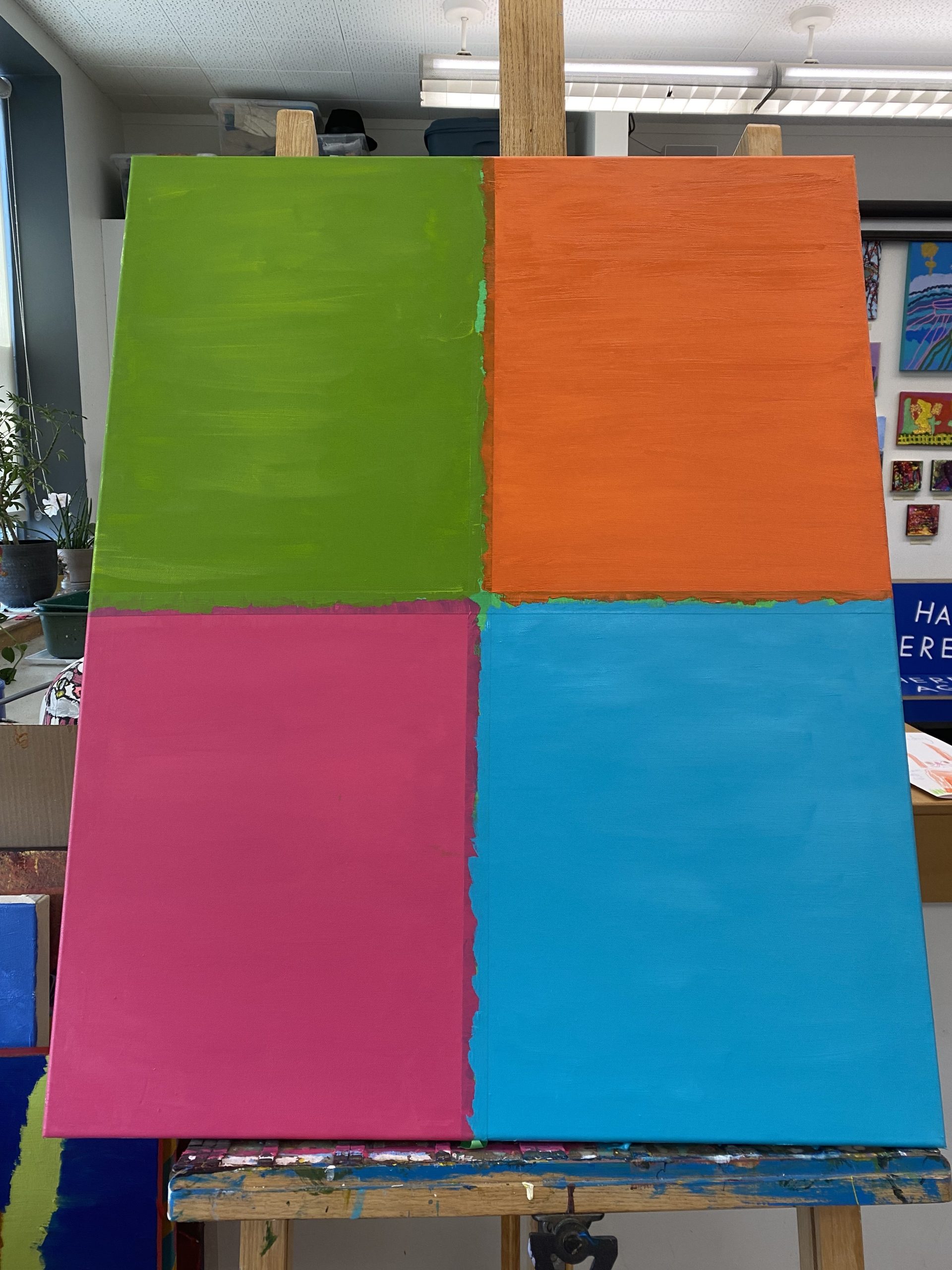 A large canvas divided into 4 oblong sections divided by a thick green line. The four sections are now complete with teh final top left painted in a rich forest green