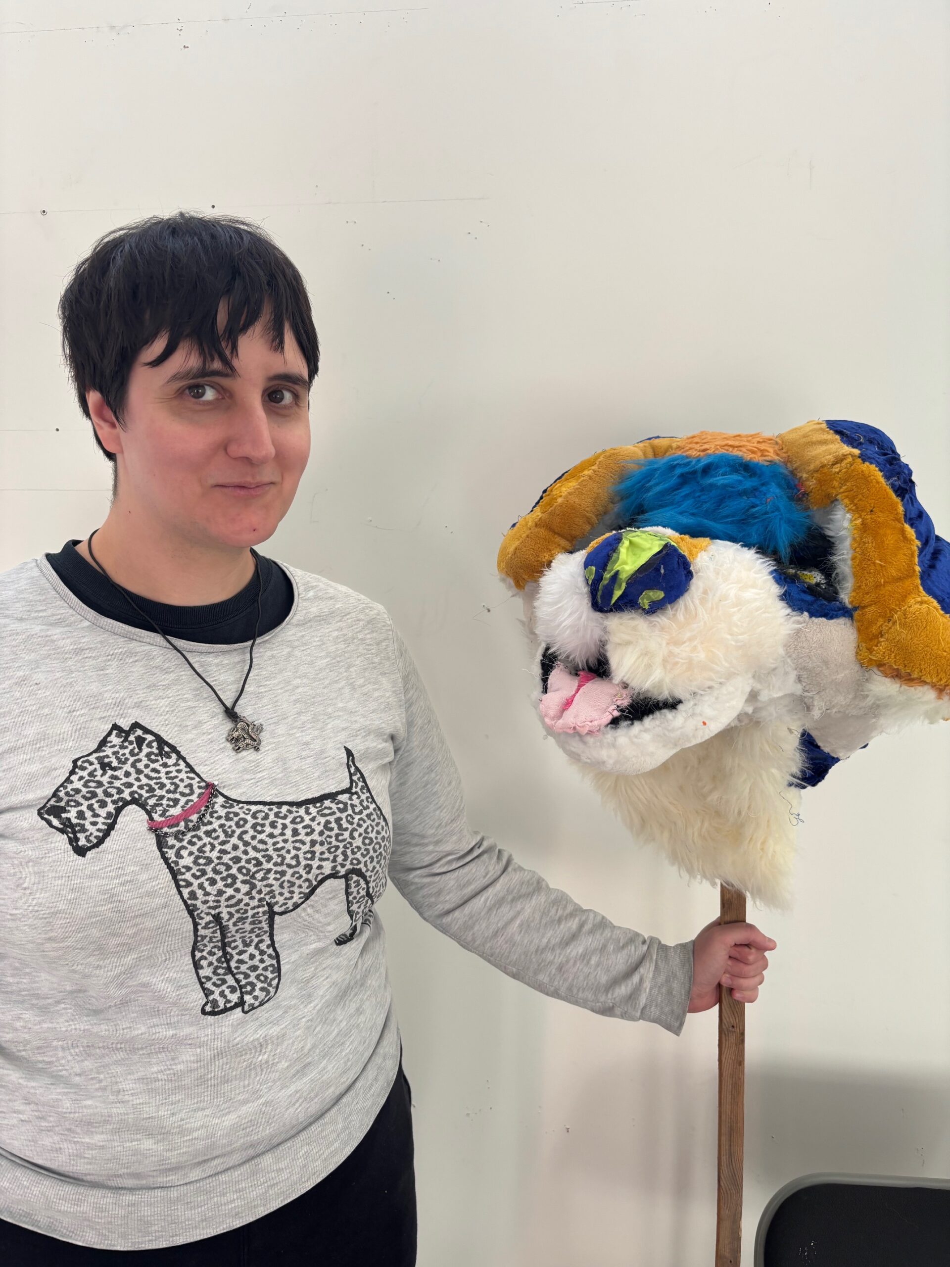 Lucy smiles at the camers holding Beagle in Blue and Yellow's head on a pole