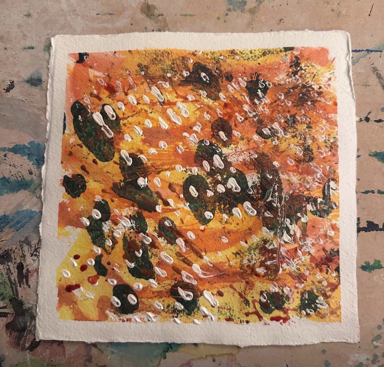 Square watercolour painting on a board. White border with yellow and orange background with thick oblong black marks in a diagonal pattern from top left hand corner to bottom right across the page. Smaller red and white marks follow the same pattern.