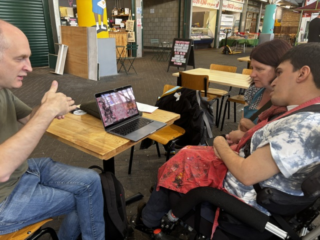 An photo of Dave Packer showing kaleidoscope images to William and Katherine