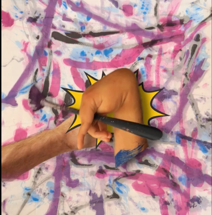 William's hands in the developing film of him painting and another hand interfering against an ink artwork he has made in purples, blacks pinks and blues